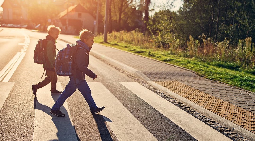 two children walking across a road
