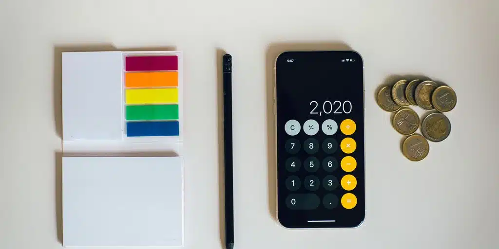 Phone with calculator app, coins, pencil, and notes